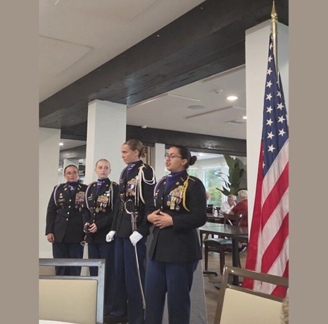 Four Cypress Lake High School JROTC cadets beside the flag at the Ladies Club meeting