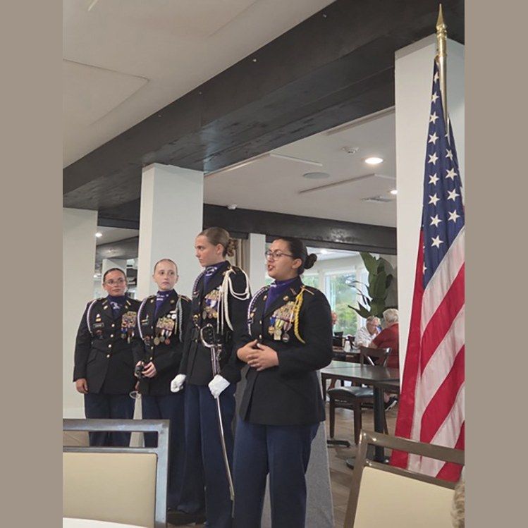 Four Cypress Lake High School JROTC cadets beside the flag at the Ladies Club meeting